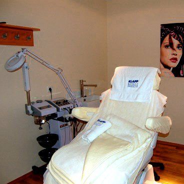 Friseurstuhl mit weißen Handtüchern, medizinischer Ausrüstung und einem Poster einer Frau.