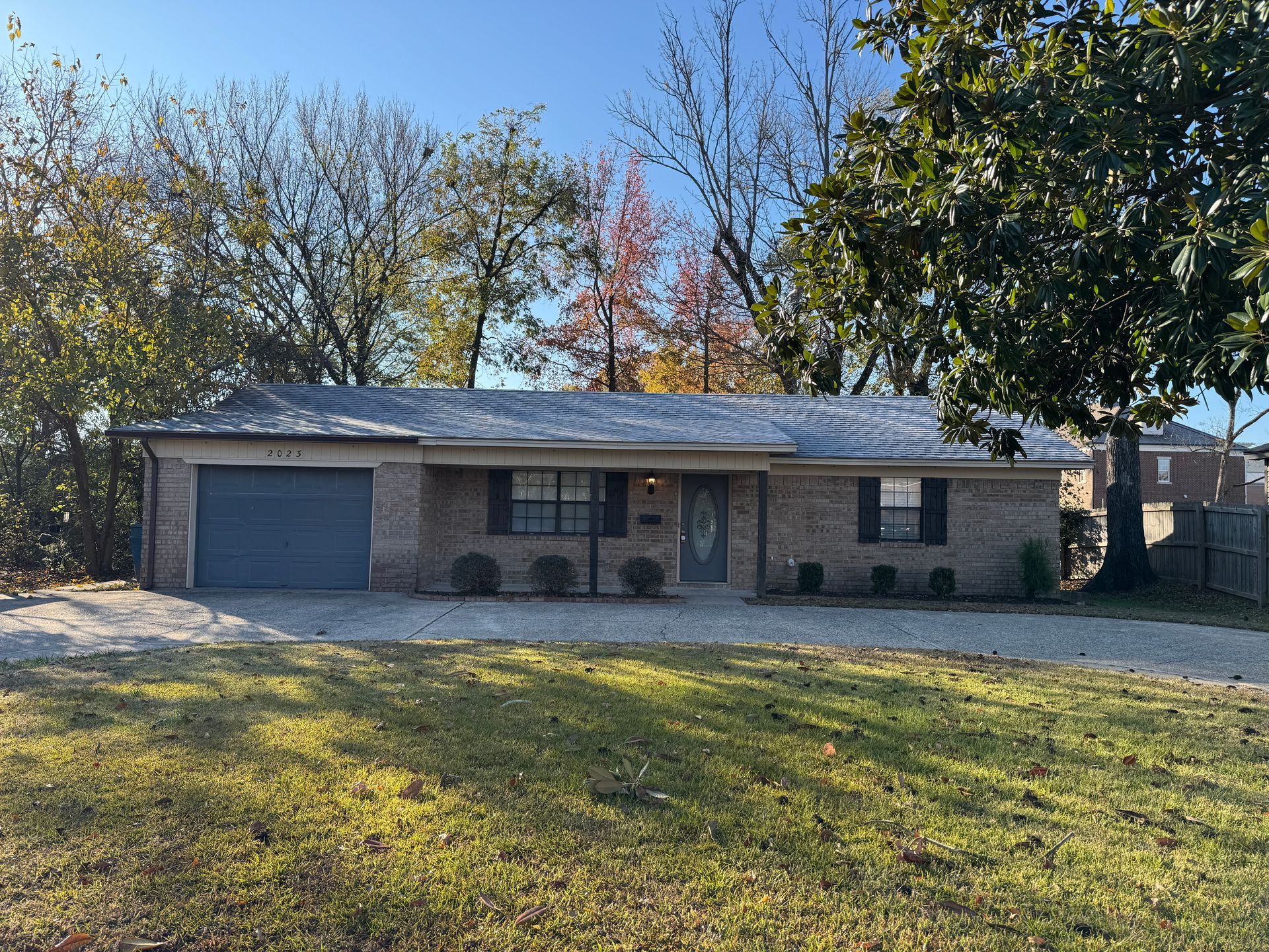 A brick house with a garage and a large lawn in front of it.