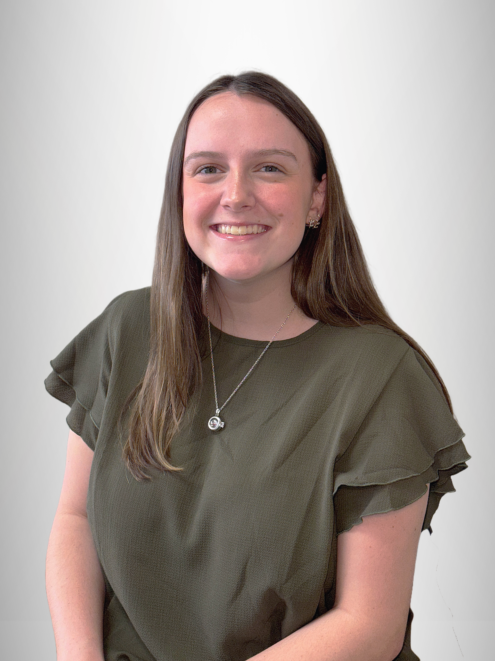 A young woman wearing a green shirt and a necklace is smiling for the camera.