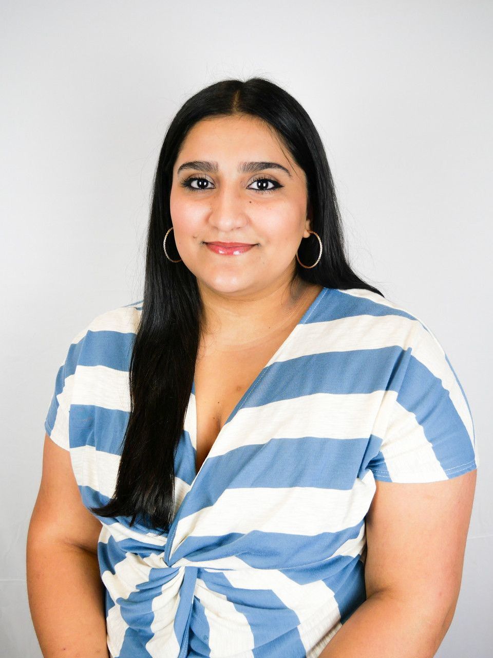 A woman in a blue and white striped shirt is smiling for the camera.