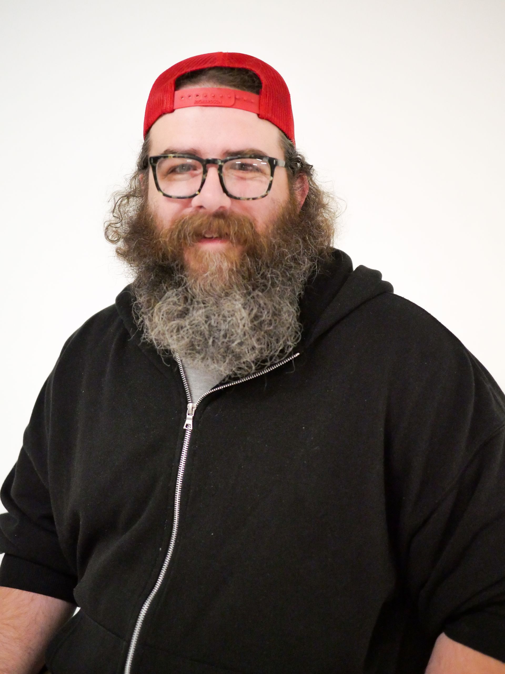 A man with a beard wearing glasses and a red hat