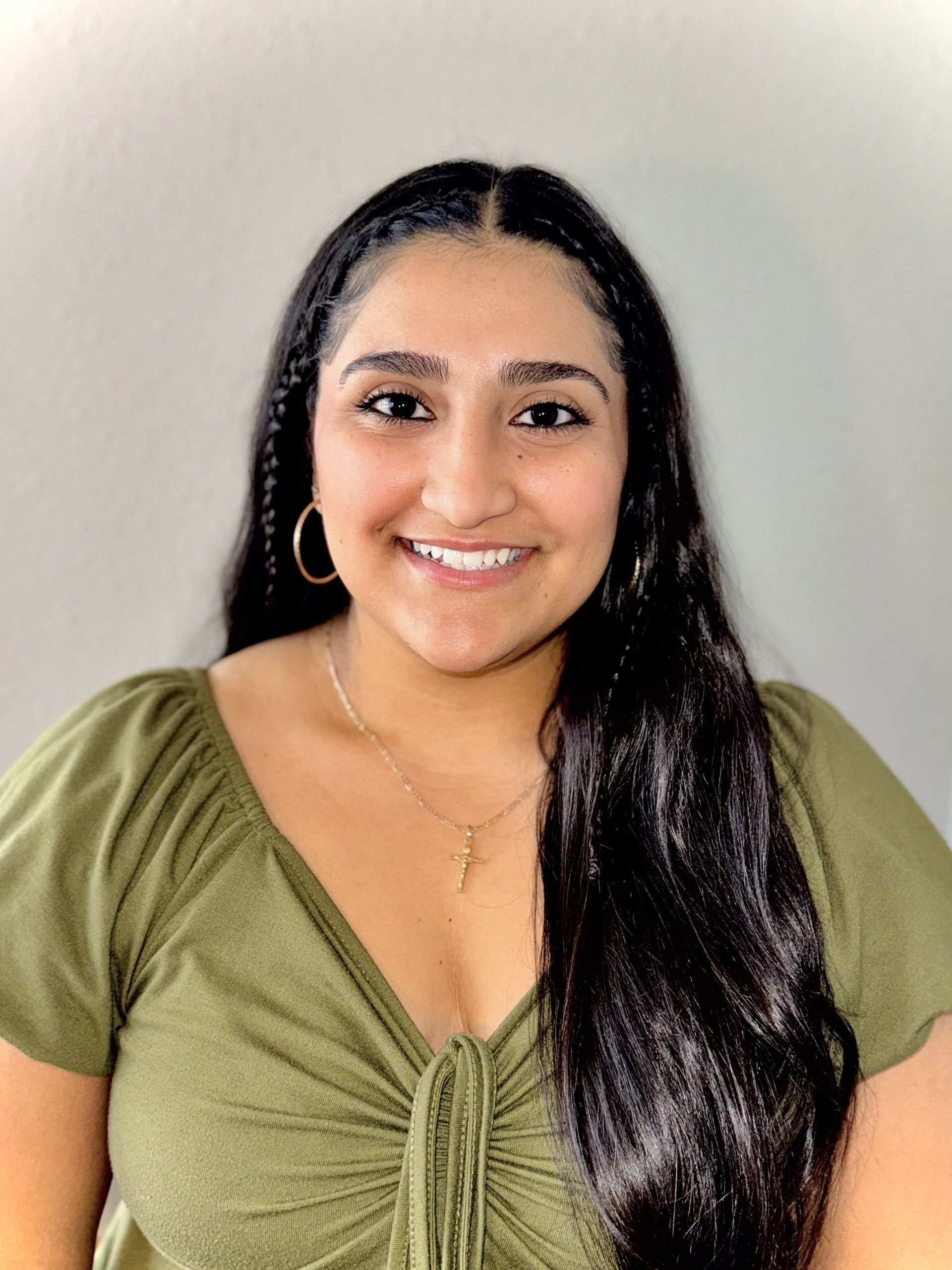 A woman with long hair is wearing a green shirt and smiling.