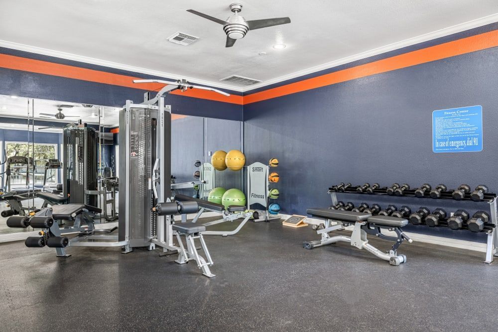 a gym with a lot of equipment and a ceiling fan at Marquis at Deerfield in San Antonio, TX.