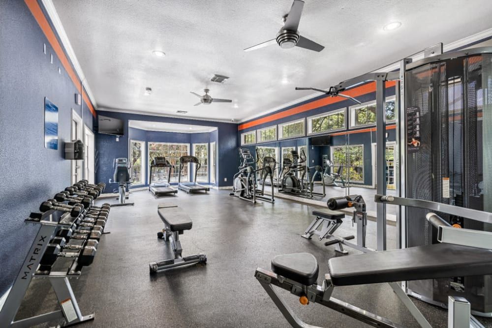 a large gym with a lot of equipment and a ceiling fan at Marquis at Deerfield in San Antonio, TX.