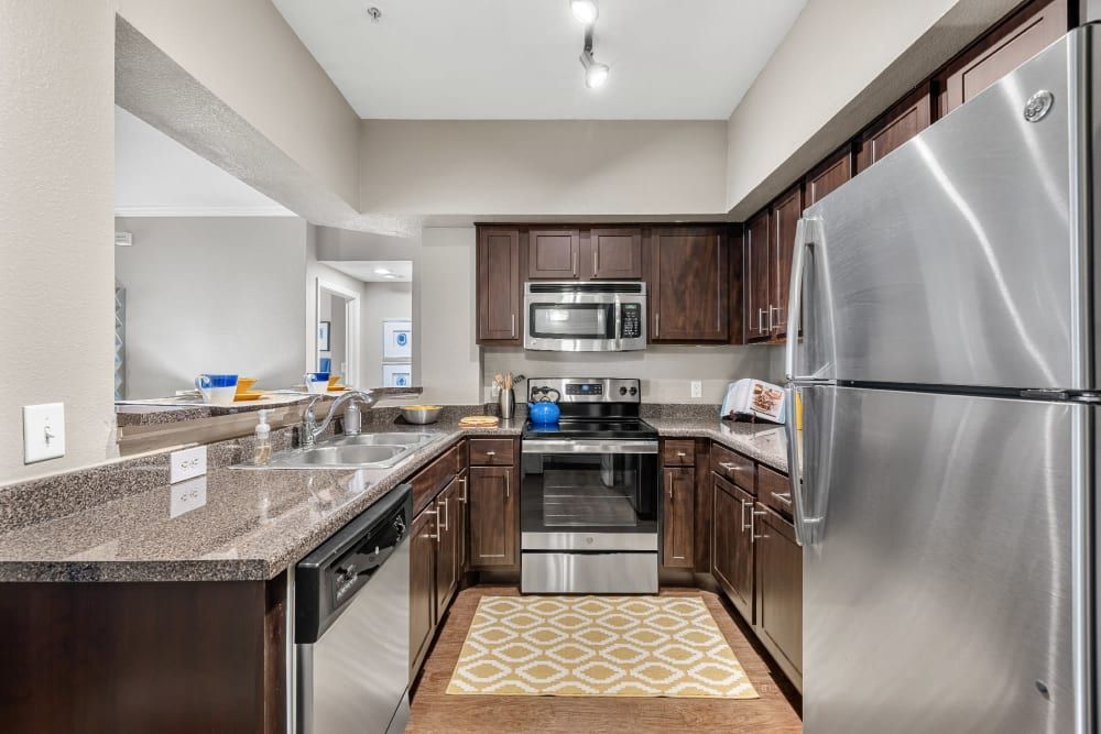 a kitchen with stainless steel appliances and wooden cabinets at Marquis at Deerfield in San Antonio, TX.