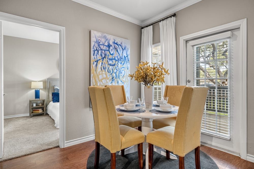 a dining room with a table and chairs and a sliding glass door leading to a balcony at Marquis at Deerfield in San Antonio, TX.