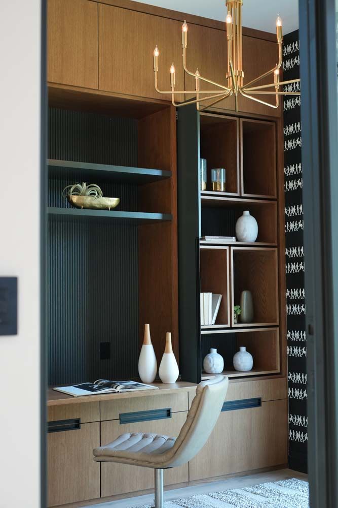 A room with a desk , chair , shelves and a chandelier