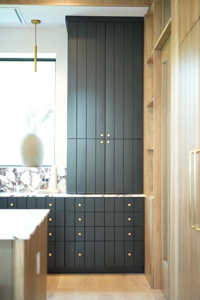 A kitchen with black cabinets and drawers and a window