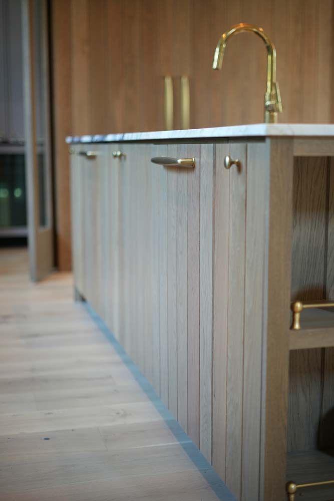 A kitchen with wooden cabinets and a brass faucet.