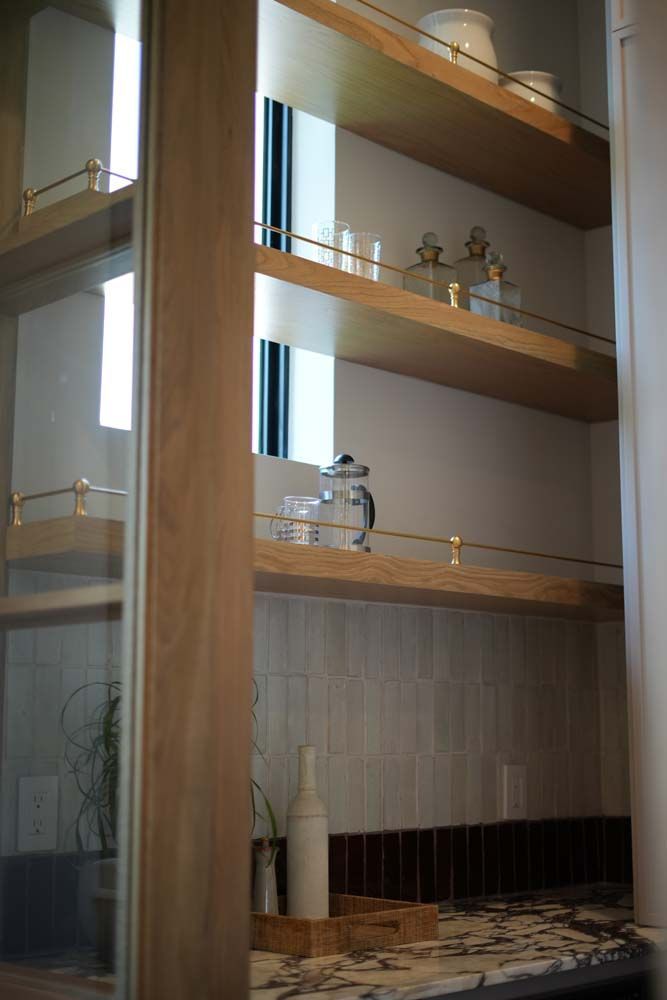 A kitchen with wooden shelves and a mirror.