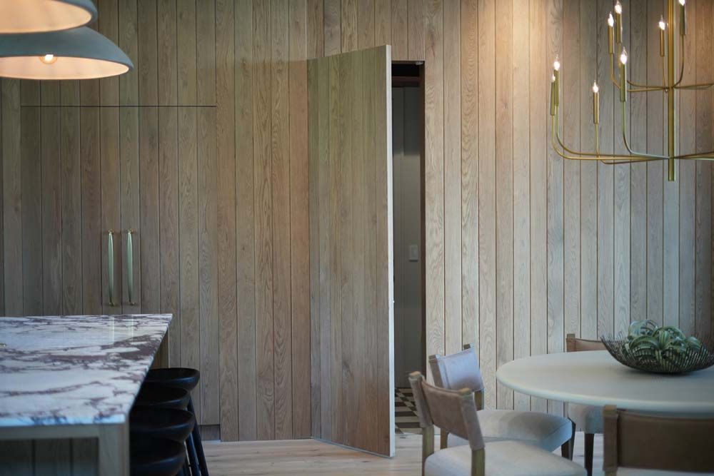 A dining room with a table and chairs and a wooden wall.