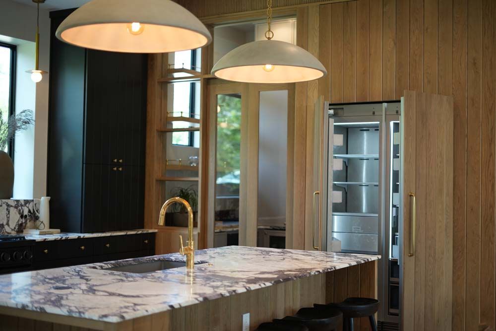 A kitchen with a large island , sink , refrigerator and stainless steel appliances.