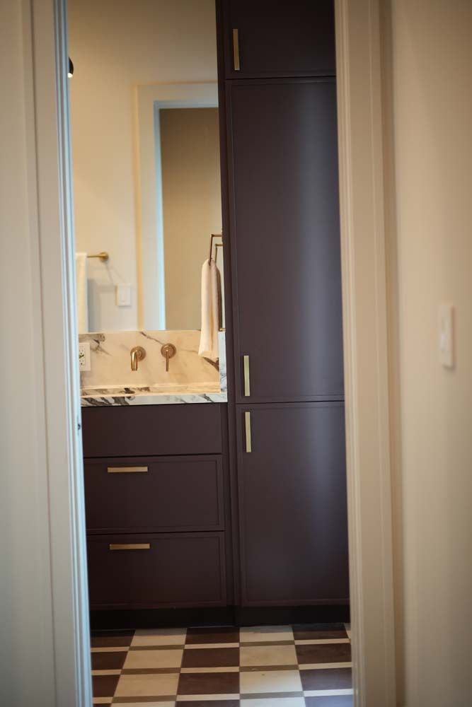 A bathroom with a sink , cabinets and a checkered floor.