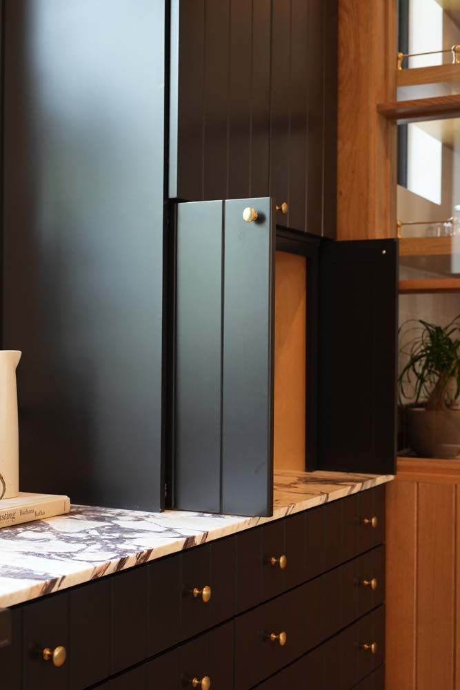 A kitchen with black cabinets and marble counter tops