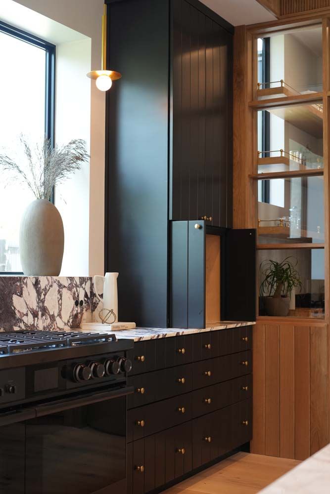 A kitchen with black cabinets , a stove , and a window.
