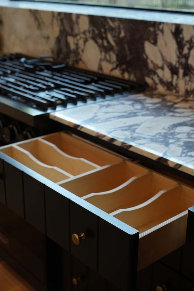 An open drawer in a kitchen with a stove top in the background