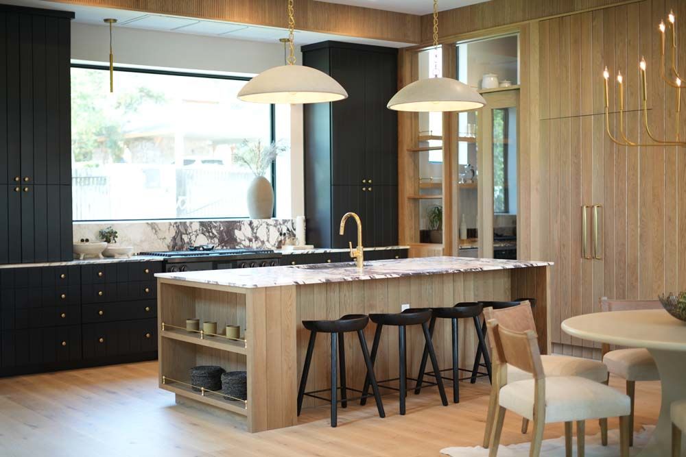 A kitchen with a large island , stools , a table and chairs.