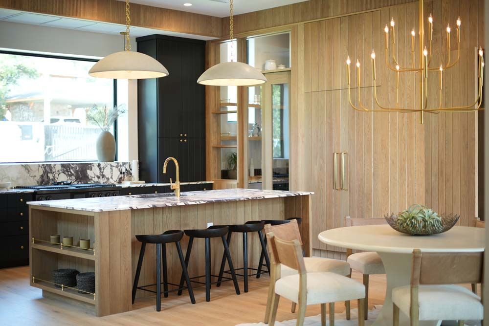 A kitchen with a large island , stools , a table and chairs.