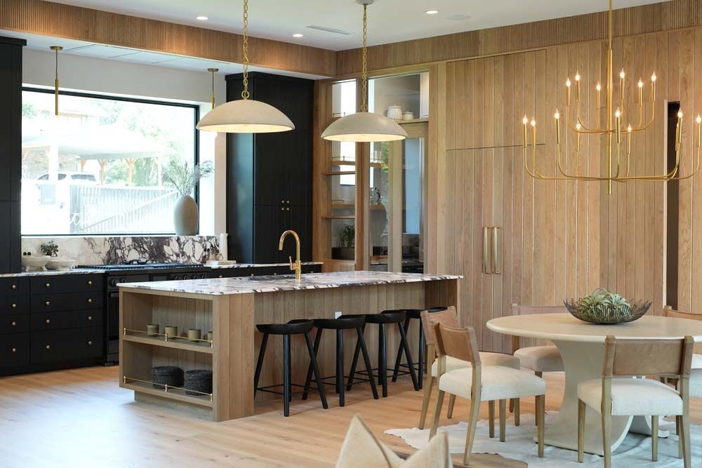 A kitchen with a large island , stools , a table and chairs.