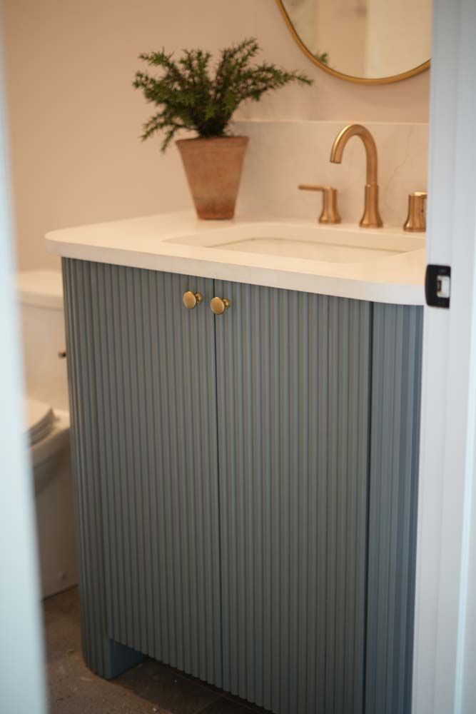 A bathroom vanity with a sink , toilet and mirror.