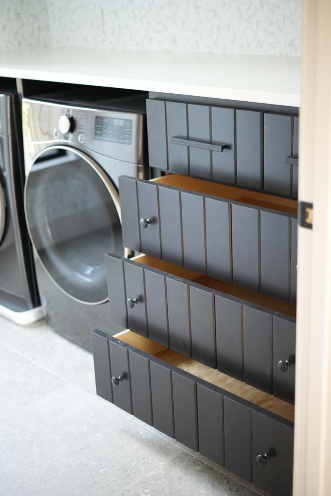A laundry room with a washer and dryer and drawers