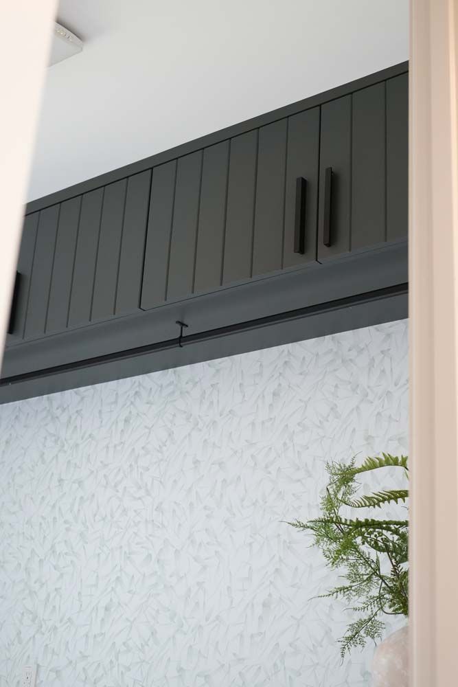 A gray cabinet is above a white wall.