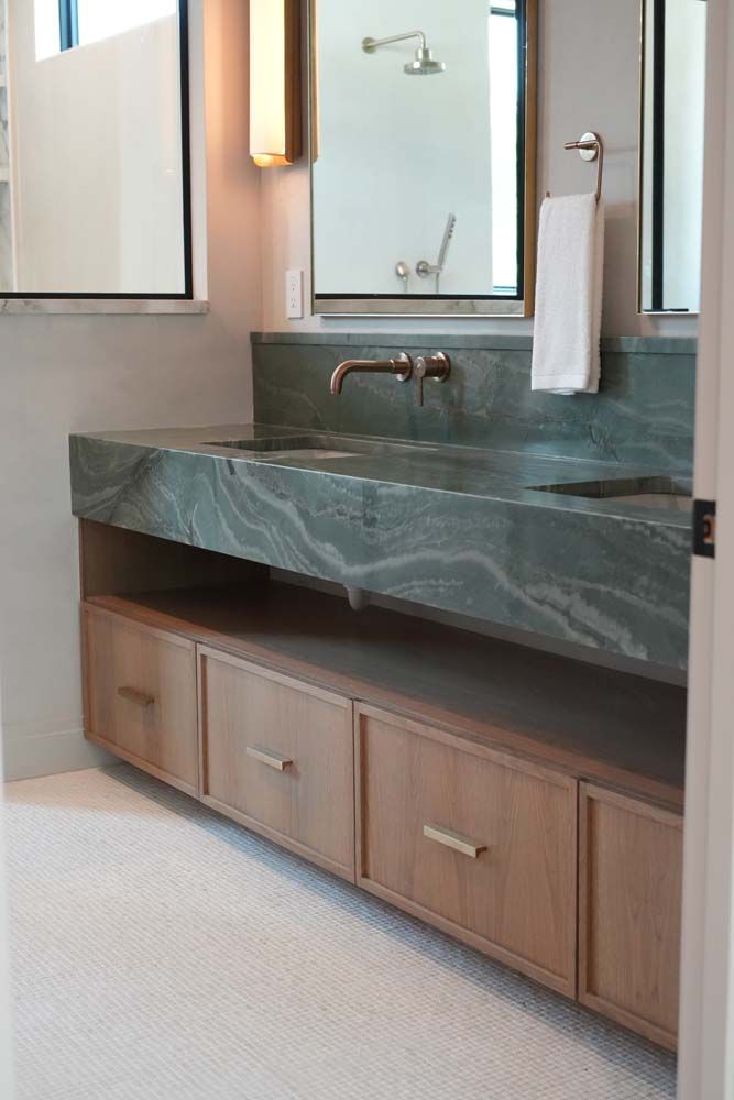 A bathroom with a sink , mirror and drawers.