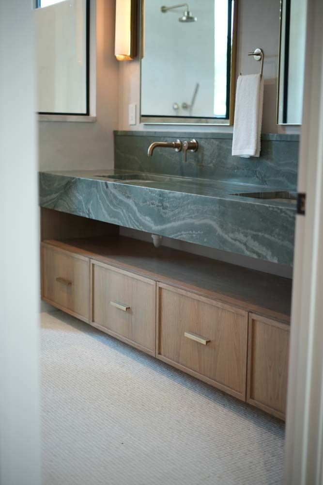 A bathroom with a sink , mirror and drawers.