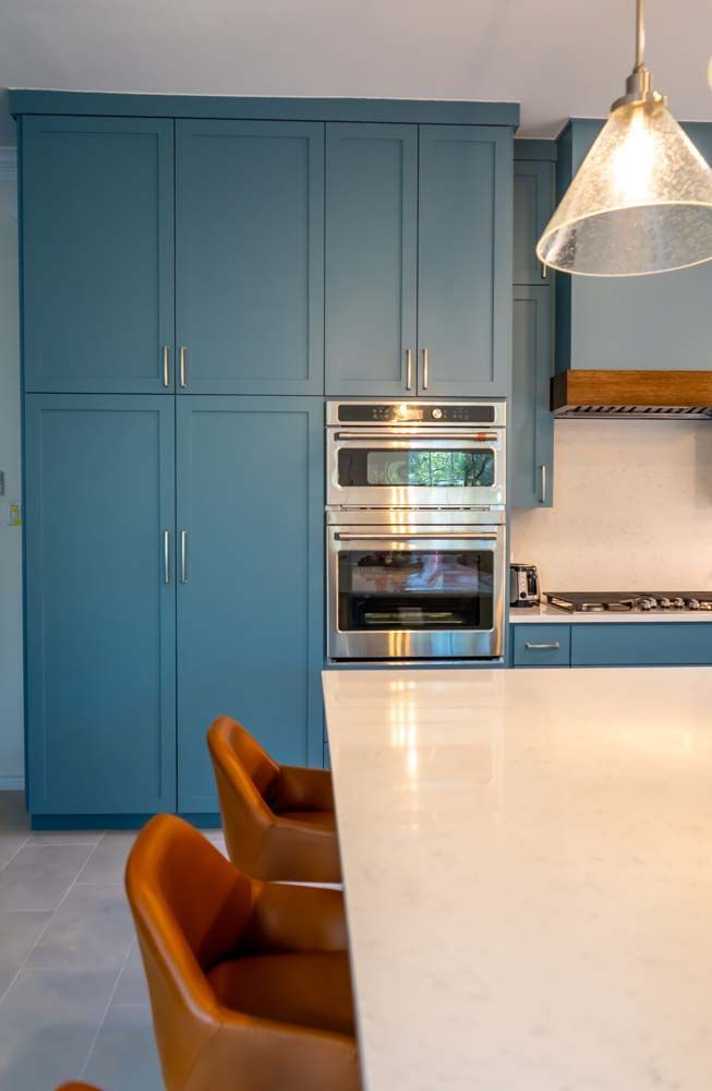 A kitchen with blue cabinets and a stainless steel oven.