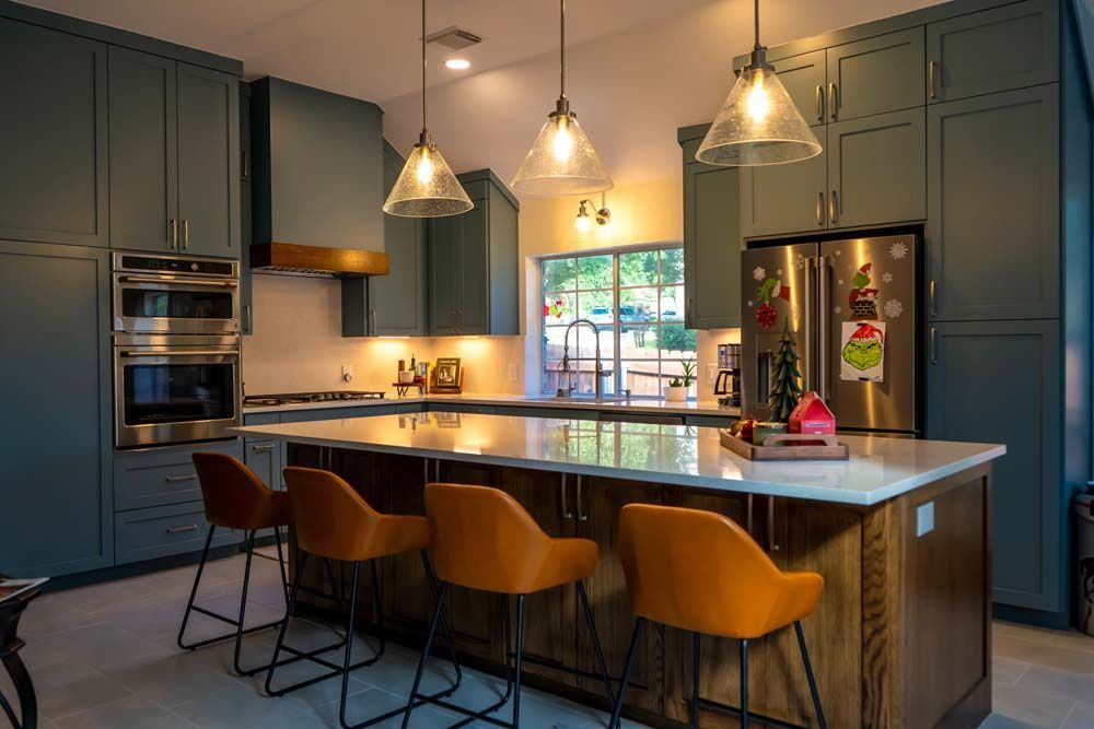 A kitchen with a large island , stools and a refrigerator.
