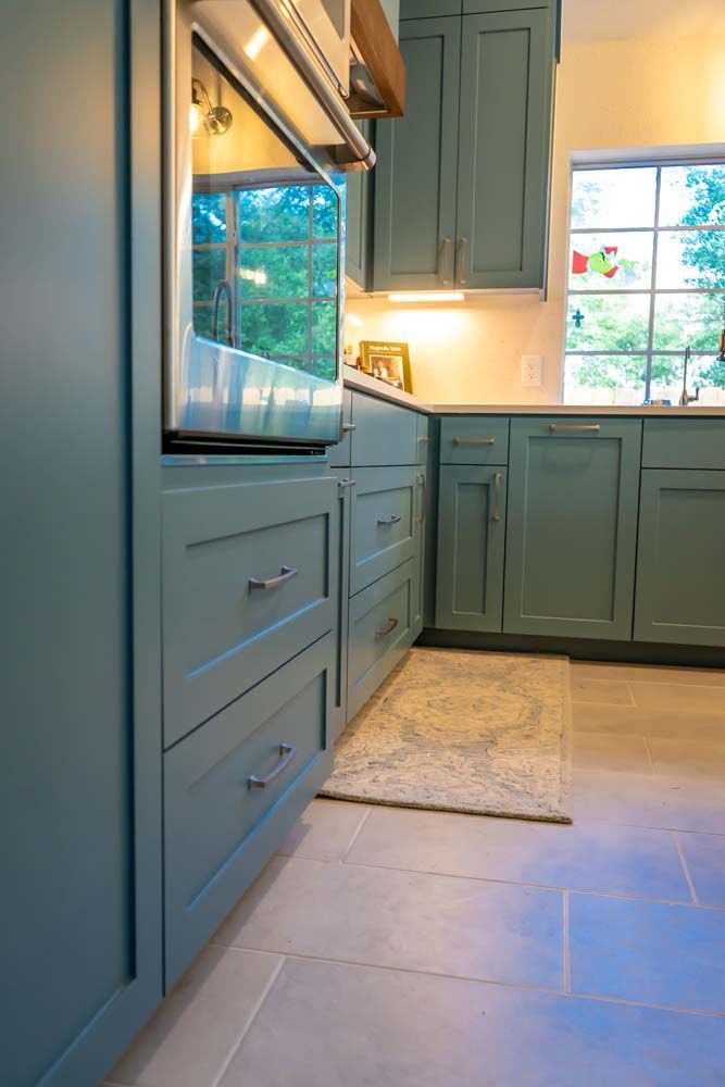 A kitchen with blue cabinets and a stainless steel oven.
