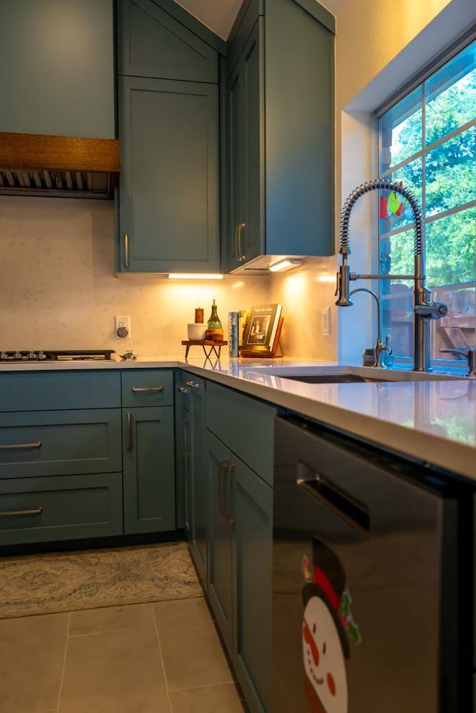 A kitchen with blue cabinets and a stainless steel dishwasher.