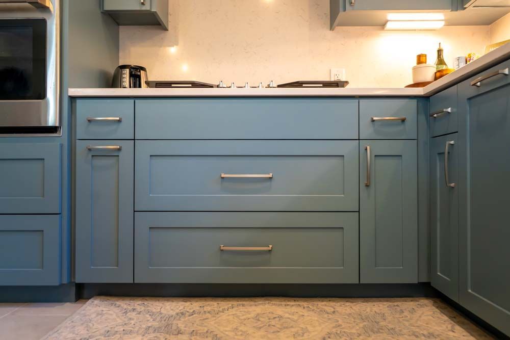 A kitchen with blue cabinets and drawers and a stove top oven.