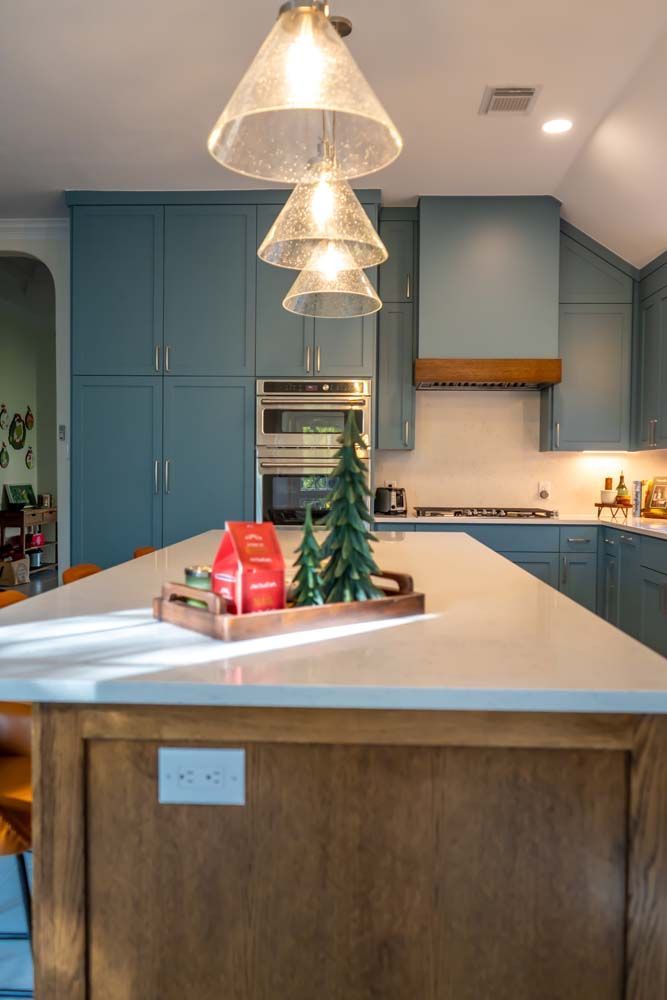 A kitchen with blue cabinets and a large island with a christmas tree on it.