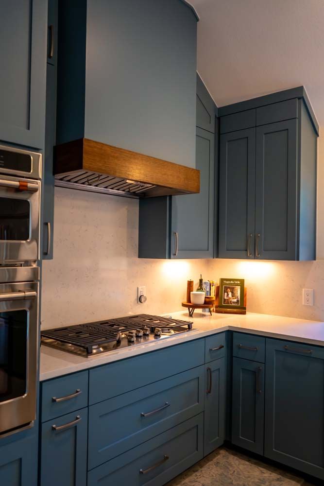 A kitchen with blue cabinets and a stove top oven.
