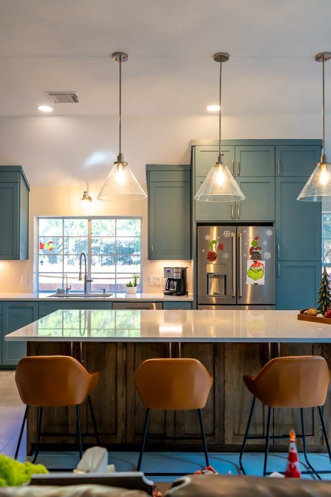 A kitchen with blue cabinets , white counter tops , stainless steel appliances , and a large island.