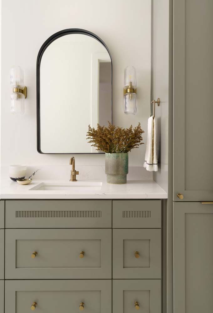 A bathroom with a sink , mirror , cabinets and drawers.