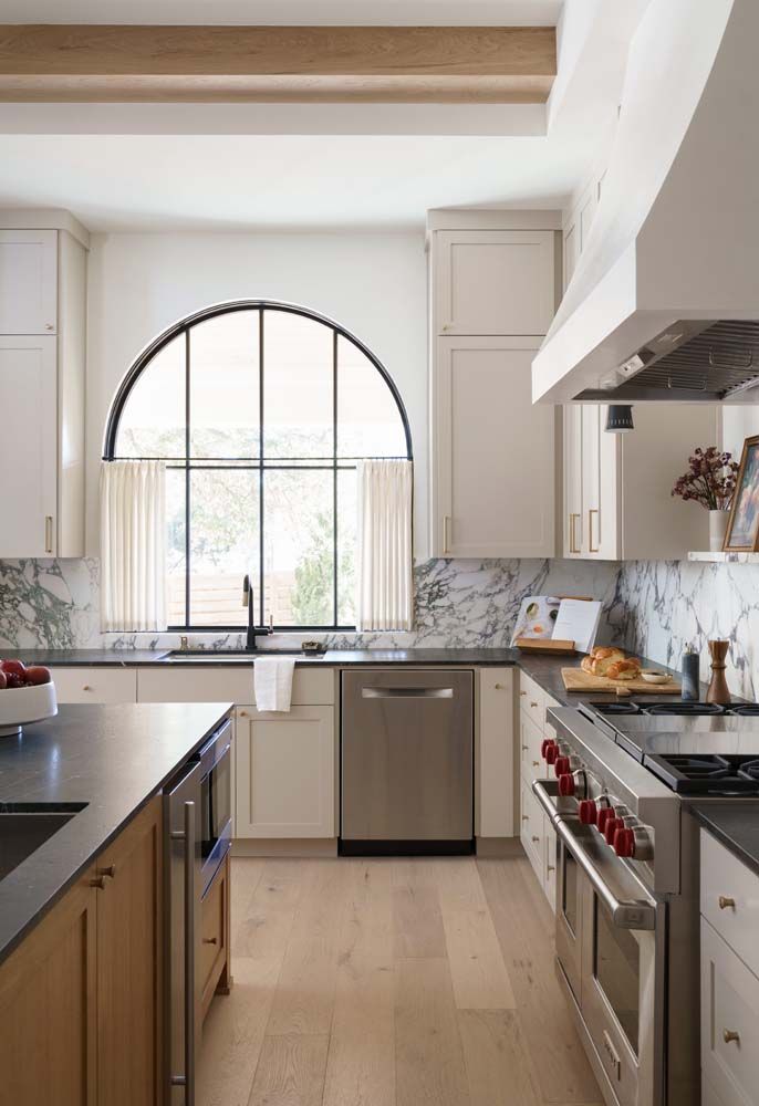 A kitchen with stainless steel appliances and a large window.