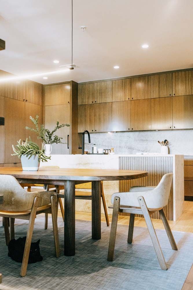 A dining room with a table and chairs and a cat on the floor.