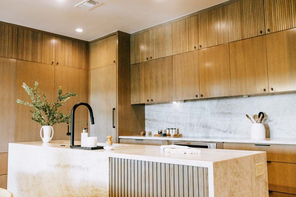 A kitchen with wooden cabinets , marble counter tops , and a large island.