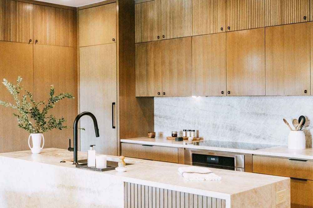 A kitchen with wooden cabinets , marble counter tops , stainless steel appliances and a large island.