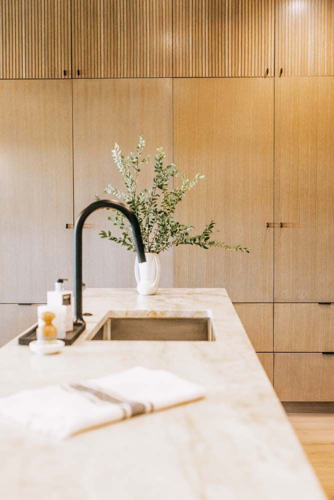 A kitchen sink with a vase of flowers on top of it.