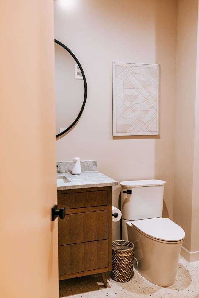 A bathroom with a toilet , sink and mirror.