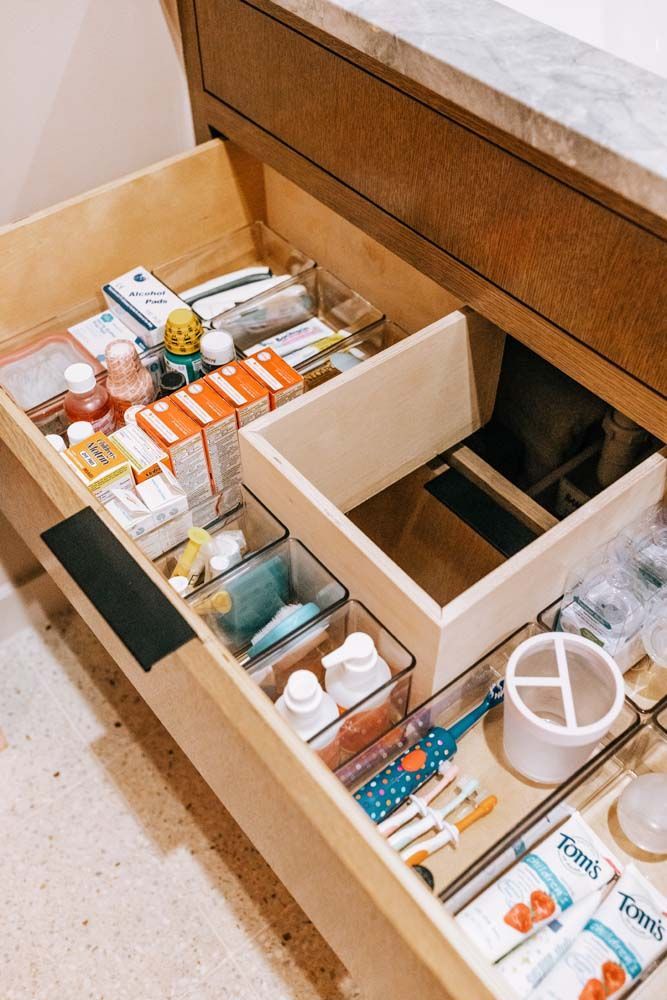 A bathroom drawer filled with lots of medicines and toothbrushes.