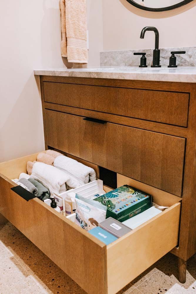 A bathroom vanity with a drawer filled with towels and toiletries.