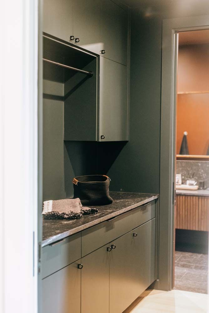 A laundry room with a sink , cabinets , and a door leading to a bathroom.