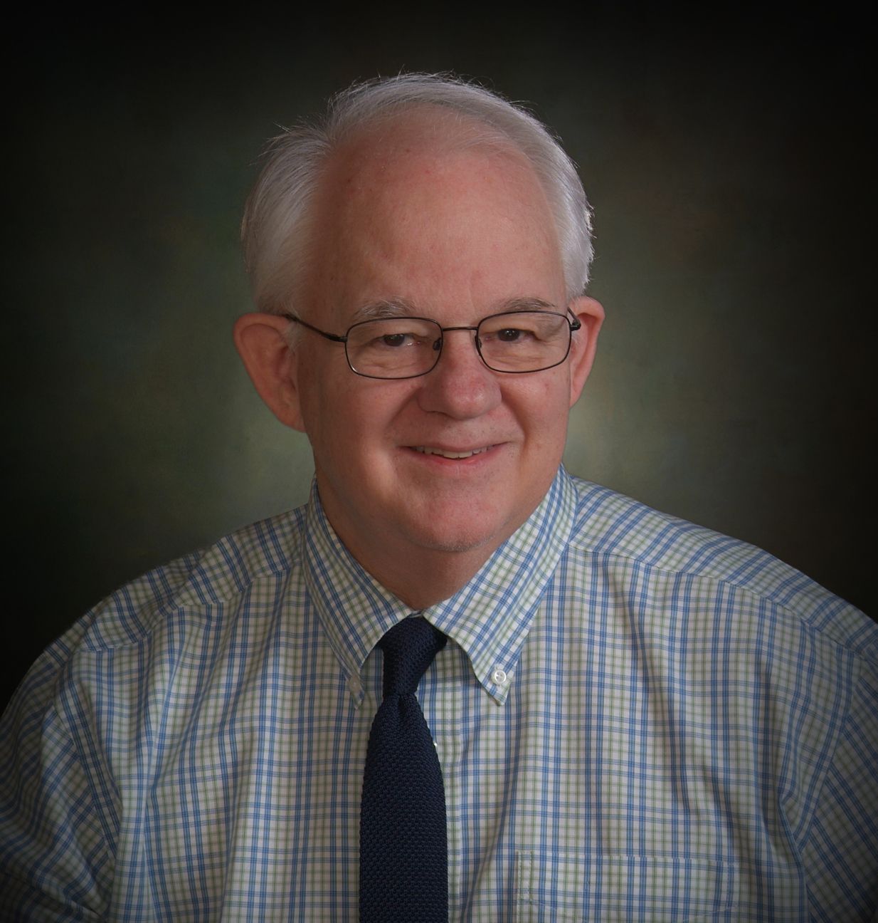 A man wearing glasses and a plaid shirt and tie