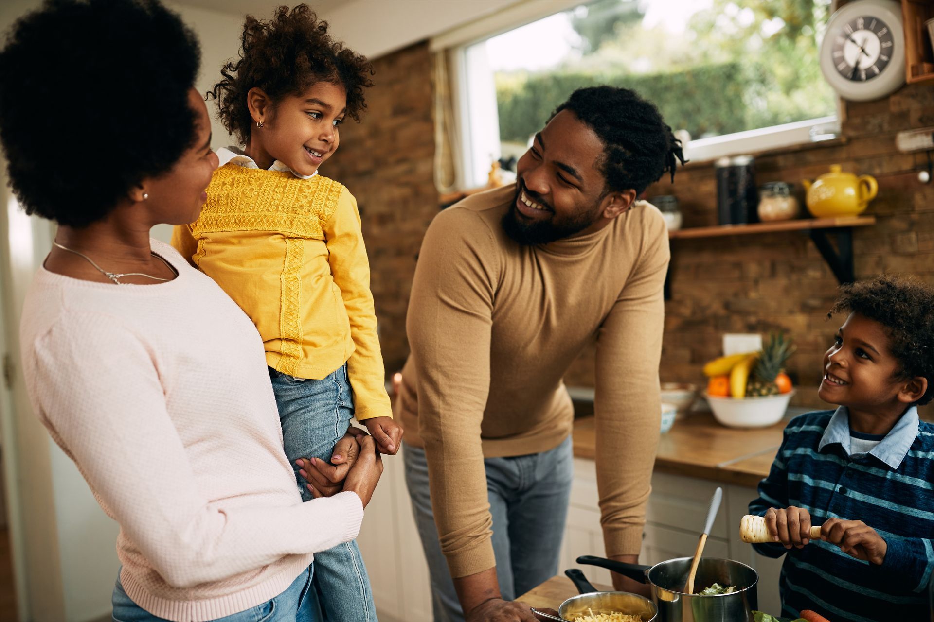 A family is standing in a kitchen preparing food together.