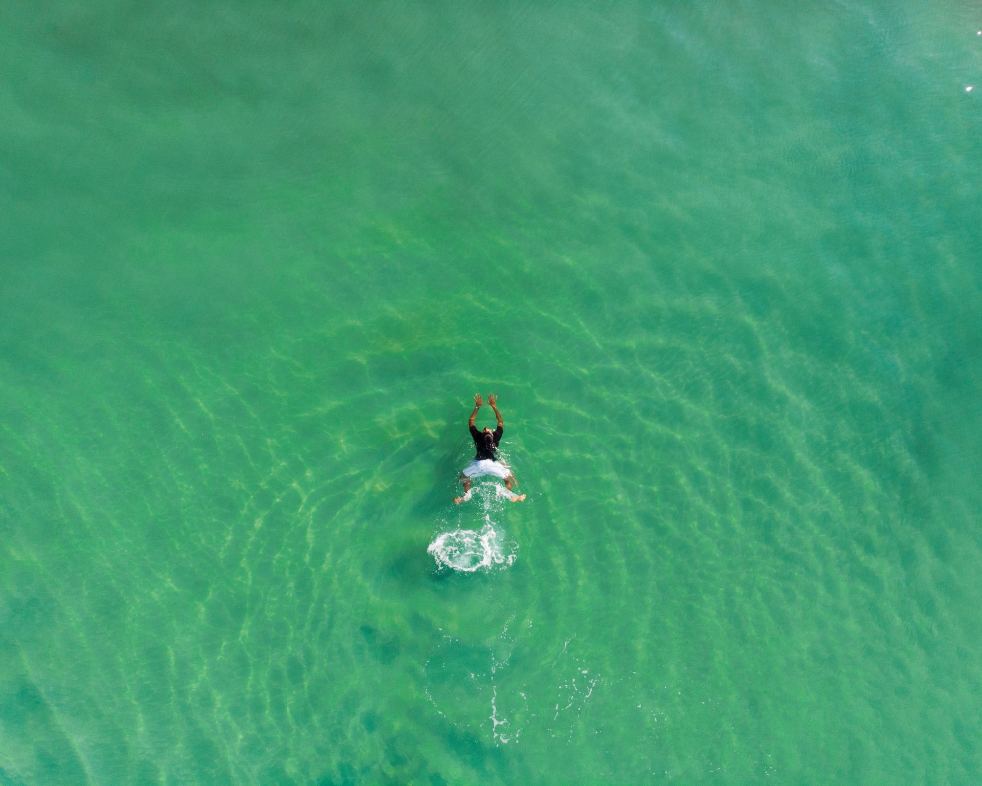 An aerial view of a person swimming in the ocean.