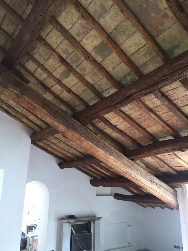 Stanza bianca con travi in ​​legno a vista sul soffitto e tegole del tetto, vista dal basso.